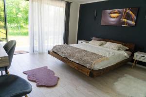 a bedroom with a large bed and a large window at Cabanutele "La Garaj" in Ocna-Mureşului