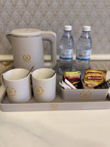a tray with two cups and two bottles of water at Hotel Madonna SPA in Kaskelen