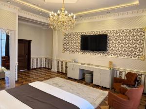 a bedroom with a bed and a tv on the wall at Hotel Madonna SPA in Qaskeleng