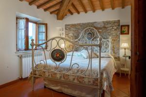ein Schlafzimmer mit einem Metallbett mit einer Steinwand in der Unterkunft GLI SPILOCCHI 16, Emma Villas in Gambassi Terme