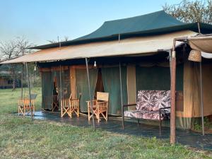 uma grande tenda verde com cadeiras e uma mesa em Zuhumath Tented Camps Serengeti em Parque Nacional Serengeti