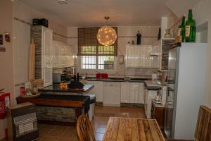 a kitchen with white cabinets and a table and a refrigerator at El bufon de la corte in Carratraca