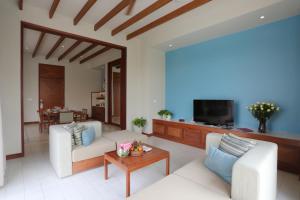 a living room with two white couches and a tv at FLC Luxury Resort Samson in Sầm Sơn