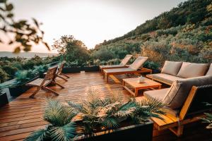 a deck with chairs and couches on top of a hill at Private Olive Glamping with Tiny House and Two Tents in Sečovlje