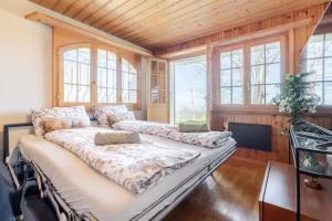 a large bedroom with a large bed and windows at Alpine View Chalet Private Garden & Lake Views in Reichenbach