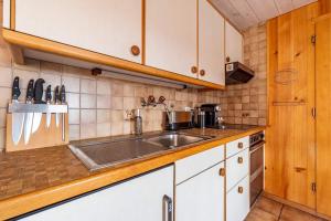 a kitchen with white cabinets and a sink at Mountainview Fireplace & Garden Bbq in Axalp