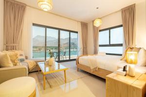 a bedroom with a bed and a living room at Facing Arabian Gulf and Mountain 4BR Villa and Assistant Room with Outdoor Pool and BBQ Space, Al Dana Island, Fujairah by Deluxe Holiday Homes in Fujairah +45 photos