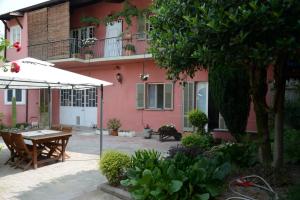 a pink house with a table and an umbrella at La Libellula Alloggio Vacanza in Chiusa di Pesio