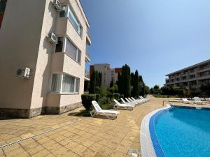 a row of lounge chairs next to a building with a pool at The Sunny Spot in Sunny Beach