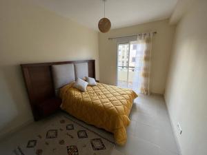une chambre avec un lit avec une couverture jaune dessus dans l'établissement Magnifique Appartement Bahia Golf Beach, à Bouznika