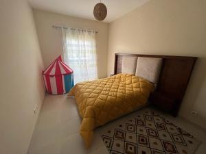 - une chambre avec un lit doté d'une couette jaune et d'une fenêtre dans l'établissement Magnifique Appartement Bahia Golf Beach, à Bouznika