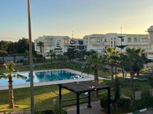 - une vue sur la piscine bordée de palmiers et de bâtiments dans l'établissement Magnifique Appartement Bahia Golf Beach, à Bouznika