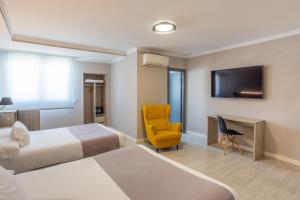 a hotel room with two beds and a yellow chair at Hotel Villa de Verín in Verín