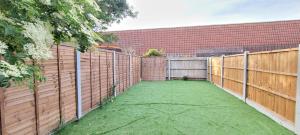 un patio trasero con una valla de madera y césped verde en Dagenham - House - Sleeps 4 - Garden - City Centre, en Dagenham