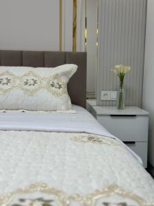 TürkistanにあるЖк Караван Сарайの花瓶の白いベッドが備わるベッドルーム1室