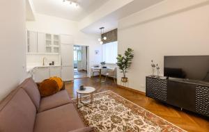 a living room with a couch and a tv and a kitchen at Grand Hotel Residents in Tartu