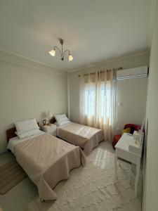 ein weißes Schlafzimmer mit 2 Betten und einem Fenster in der Unterkunft A nest for two in Athens in Mesochórion