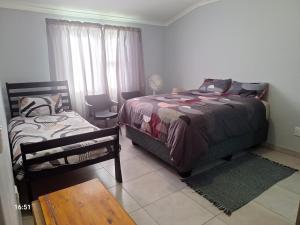 a bedroom with a bed and a chair and a table at Huigu Homestay Accommodation in Walvis Bay