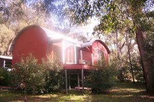 a small red house in the middle of trees at Heavenly Retreat in Halls Gap