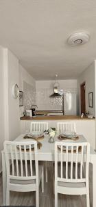 cocina con mesa blanca y 2 sillas blancas en Edén Los Cristianos, en Los Cristianos