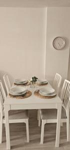 una mesa blanca con sillas y un reloj en la pared en Edén Los Cristianos, en Los Cristianos