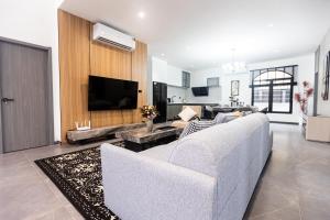 a living room with a white couch and a tv at Sun Sky Pool Villa 5 Bed Group Friendly BBQ KTV in Pattaya South