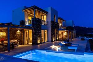 a villa with a swimming pool at night at Soborgo Exquisite Villas in Tinos
