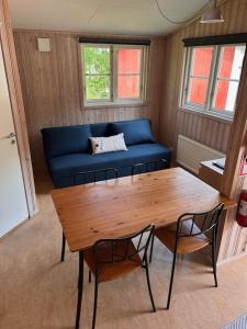 a living room with a table and a blue couch at Bredsands camping och bad- Bredsandsstugor in Enköping