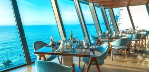 a restaurant with tables and chairs and the ocean at Boton Blue Hotel & Spa in Nha Trang