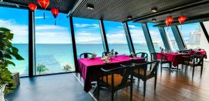 a dining room with tables and chairs and the ocean at Boton Blue Hotel & Spa in Nha Trang