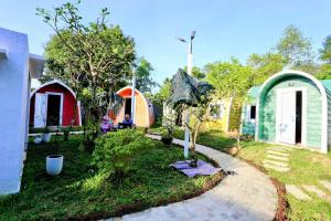 un jardin avec des maisons colorées et une passerelle dans l'établissement Minh Hầu Lạc Trú Homestay, à Ấp Long Hồ Hạ 5 autres photos