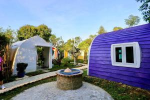une maison violette avec un chapeau sur une souche d'arbre dans l'établissement Minh Hầu Lạc Trú Homestay, à Ấp Long Hồ Hạ