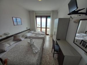una camera d'albergo con due letti e uno specchio di Hotel Europa a Gabicce Mare