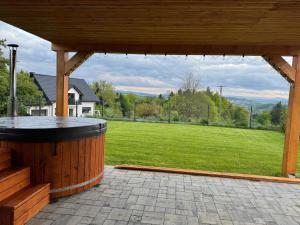 a large patio with a hot tub and a green field at Stodoła skamieniałe wzgórze in Tursko