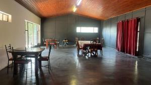a room with tables and chairs and red curtains at Miners Rest Lodge in Phalaborwa