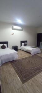 1 dormitorio con 2 camas y alfombra en el suelo en العييري للشقق المخدومة القصيم 4, en Buraidah