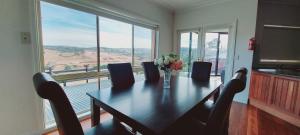 una mesa de comedor con sillas y un jarrón de flores en Luxurious stay with amazing views, en Bacchus Marsh