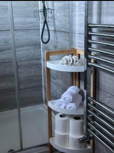 a bathroom with two shelves with towels and a shower at Luxury Modern Comfy 3BR House Contractors Family in Kettering