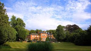 a large brick house in a field with trees at Brandshatch Place Hotel & Spa in Dartford