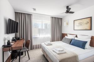 a hotel room with a bed and a desk with a computer at AIRINN Vilnius Airport Hotel RENOVATED 2025 in Vilnius