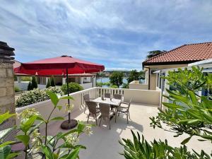 a patio with a table and a red umbrella at Apartments Scheich in Šilo