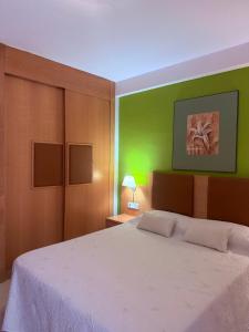 a bedroom with a white bed with a green wall at Preciso atico con jacuzzi en Laguna Beach in Vera