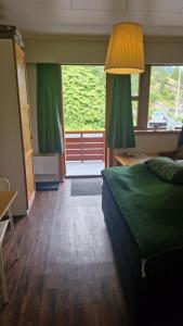 una camera con un letto verde e una grande finestra di Kvamsdal Pensjonat 2 a Eidfjord