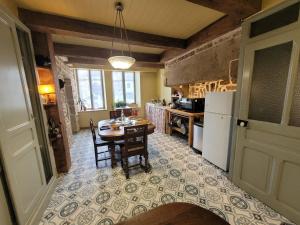 a kitchen with a table and a white refrigerator at Maison Coeurdacier 15 personnes 6 chambres in Monthureux-sur-Saône