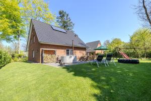 Una casa con un patio con dos sillas y un fogón. en Ferienhaus Hünzingen № 2, en Walsrode