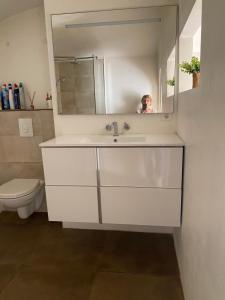a bathroom with a sink and a person in a mirror at T2 Sartène centre ville in Portigliolo