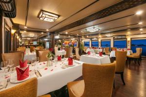 un restaurante con mesas blancas y sillas con servilletas rojas en Star Boutique Cruise, en Ha Long
