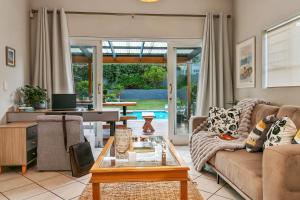 un soggiorno con un divano e un tavolo di Hot Tub Haven - Back up electricity Plett a Plettenberg Bay
