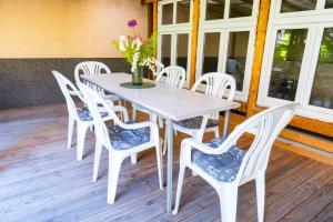 a table with white chairs and a vase with flowers at BetterBeds BRB - Apartment - Zentral - Smart TV - Küche - WLAN in Brandenburg an der Havel