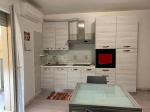 a kitchen with white cabinets and a glass table at Apartment Venezia East in Quarto dʼAltino